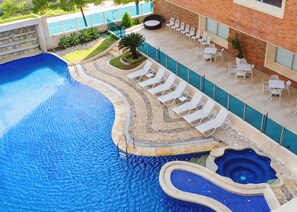 A swimming pool with a curved edge, lounge chairs, and a small hot tub. - Dann Carlton Barranquilla (Barranquilla)