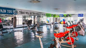 Ett gym med olika typer av träningsredskap, en motivationsvägg och en blå banner.