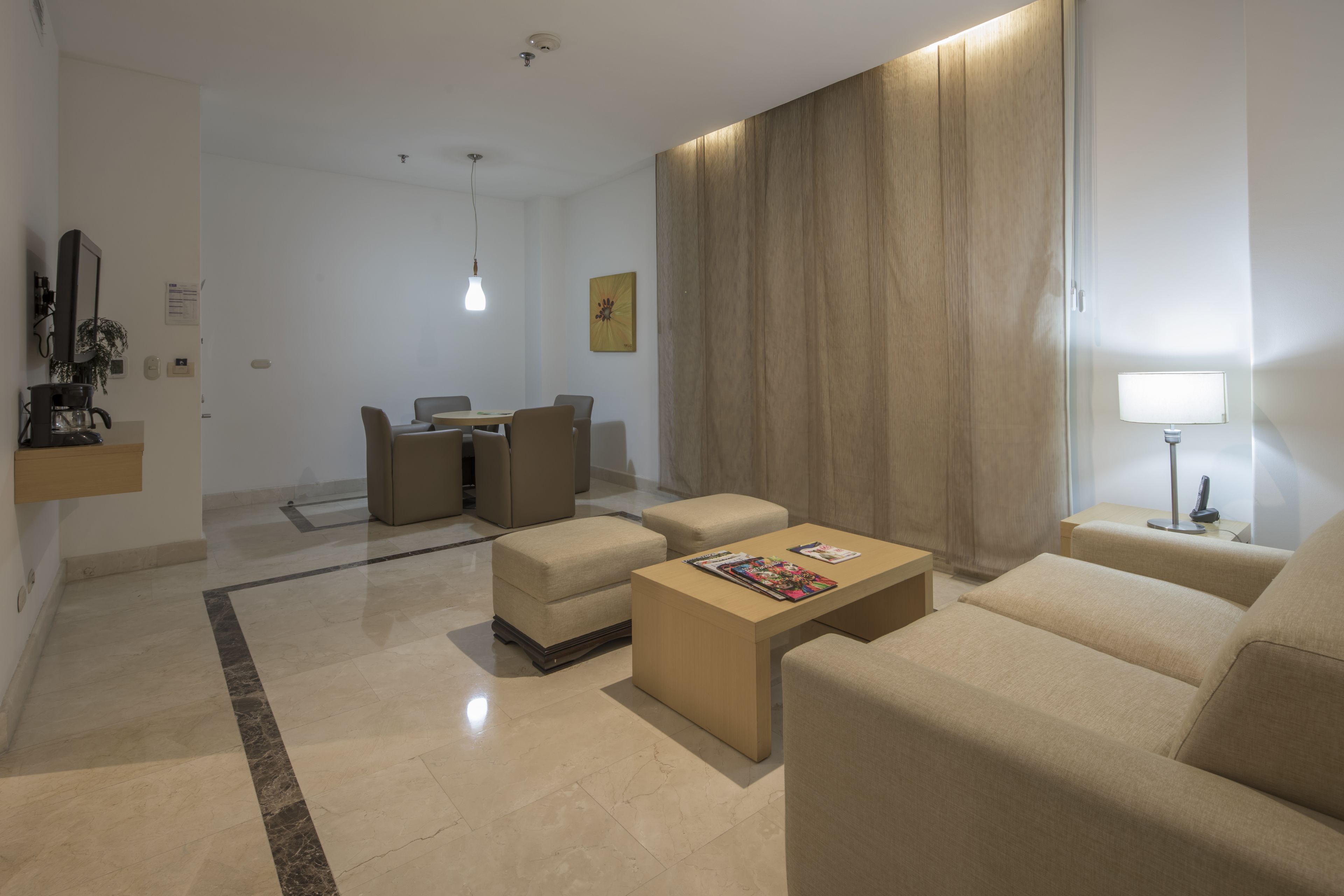 Un salon moderne avec un coin repas, comprenant un canapé, un pouf et une table basse avec des magazines.