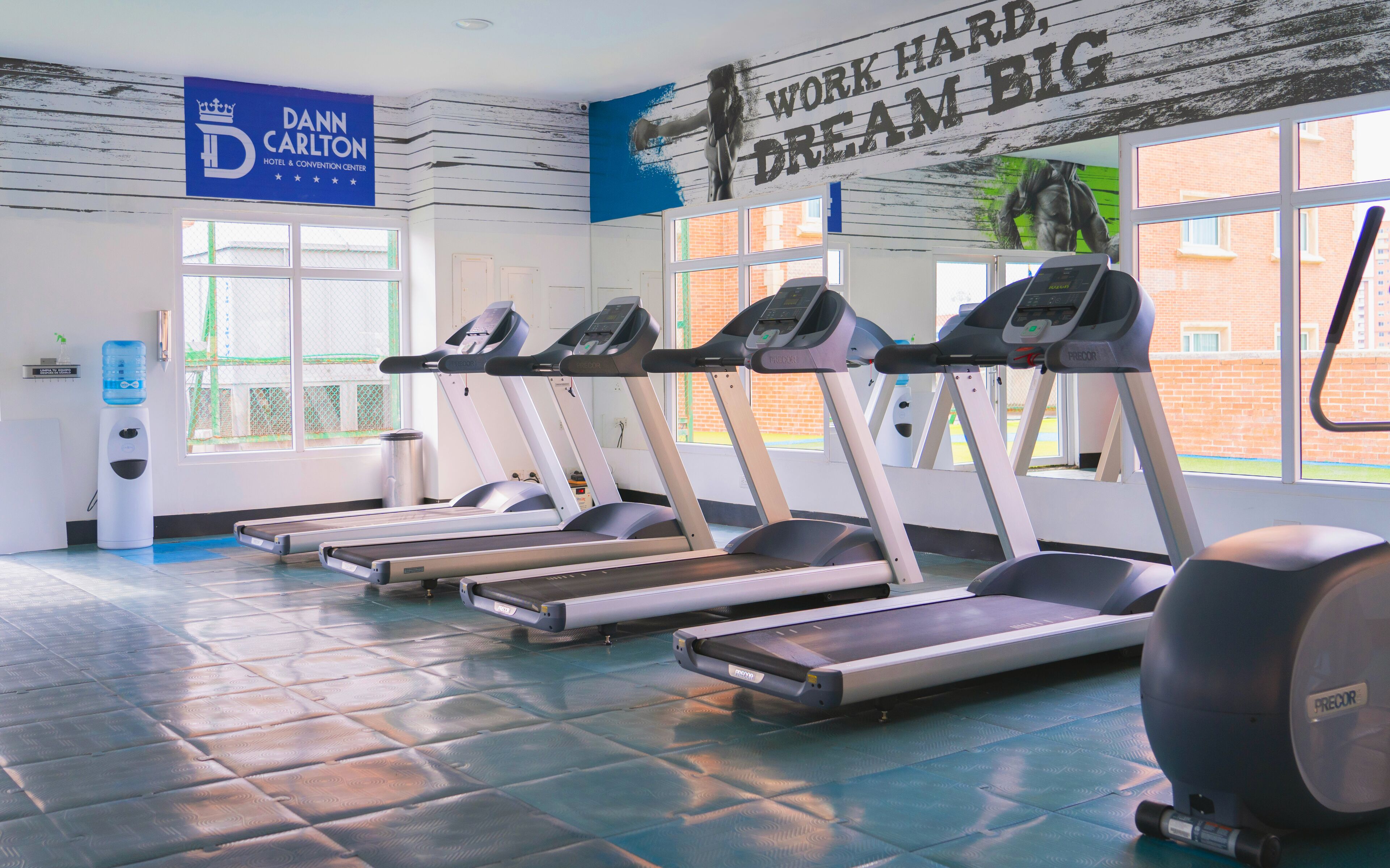 A gym with treadmills, a water dispenser, and a motivational quote on the wall.