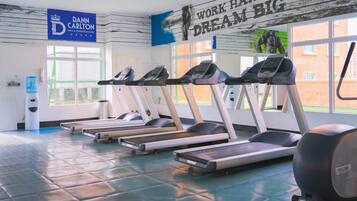 A gym with treadmills, a water dispenser, and a motivational quote on the wall.