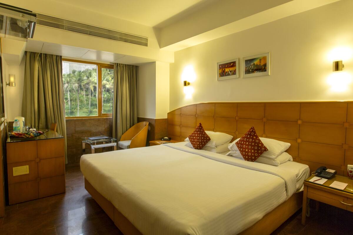 Habitación de hotel con una cama grande, un escritorio, una silla y una ventana con cortinas.