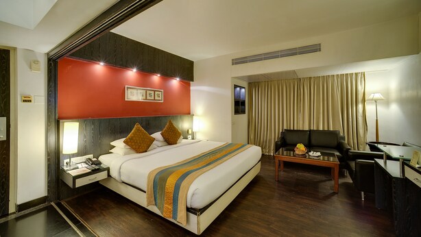 Ein Hotelzimmer mit Bett, Nachttisch, Lampe und Schreibtisch mit Stuhl.