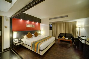A hotel room with a bed, bedside table, lamp, and a desk with a chair. - Ramee Guestline Hotel Khar (Mumbai)