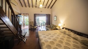 A hotel room with a bed, a chair, a table, and a staircase. - Smith & Appy Nagoa (Calangute)