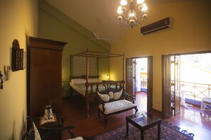 A bedroom with a four-poster bed, a wooden chair, a table, and a chandelier. - PRESA di GOA (Calangute)