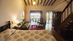 A bedroom with a bed, a desk, a chair, and a staircase. - Smith & Appy Nagoa (Calangute)
