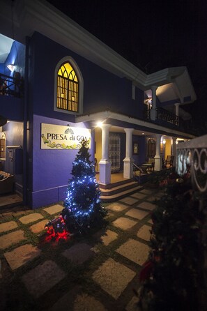 A building with a sign reading "PRESA di GOA" and a Christmas tree with lights.