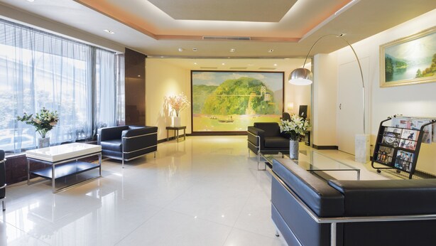 Een moderne lobby met een groot schilderij, een receptiebalie, een zithoek en een tijdschriftrek.