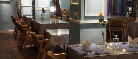Un restaurante con una larga mesa de madera, sillas y un florero con una sola flor.