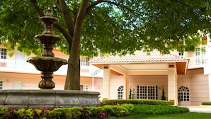 A fountain, a tree, and a building with a tiled roof and balconies. - Hotel Real del Bosque Golf and Spa (Tula de Allende)