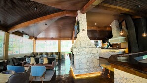 A spacious indoor area with a stone fireplace, wooden ceiling beams, and a coffee bar. - Hotel Real del Bosque Golf and Spa (Tula de Allende)