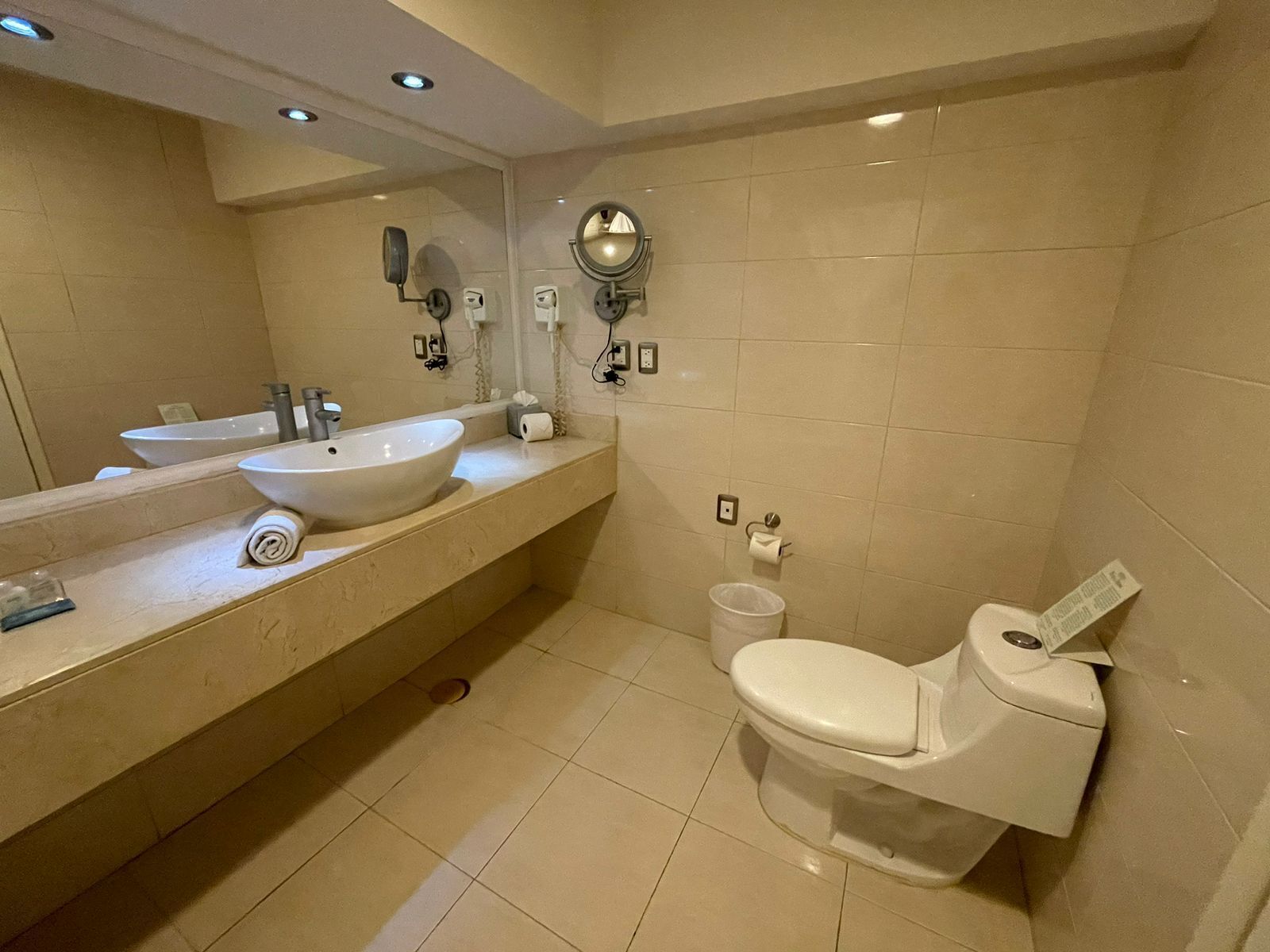 A modern bathroom with a large sink, a toilet, and a mirror.