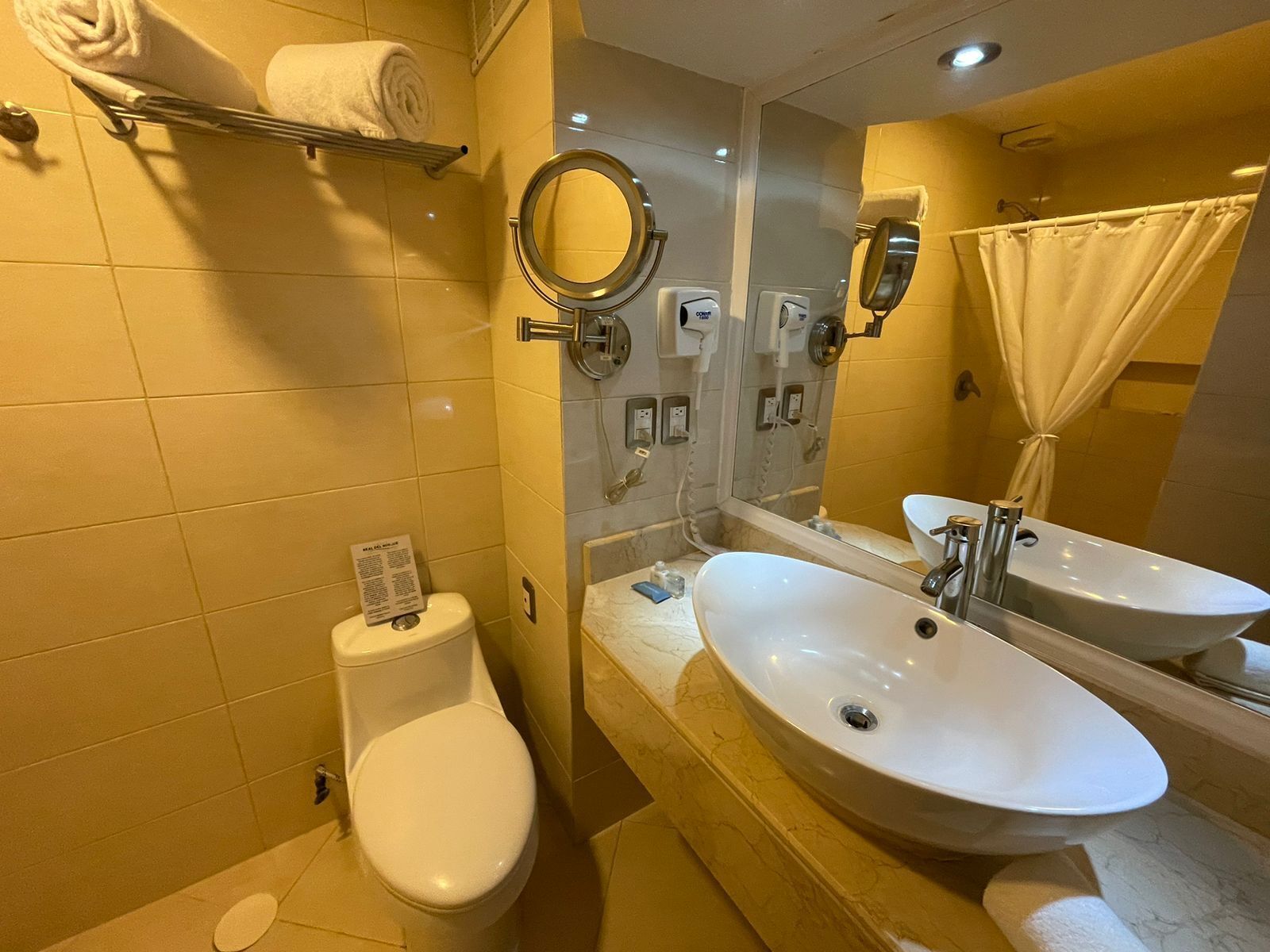 A bathroom with two sinks, a toilet, a mirror, and a towel rack.