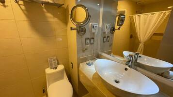 A bathroom with two sinks, a toilet, a mirror, and a towel rack.