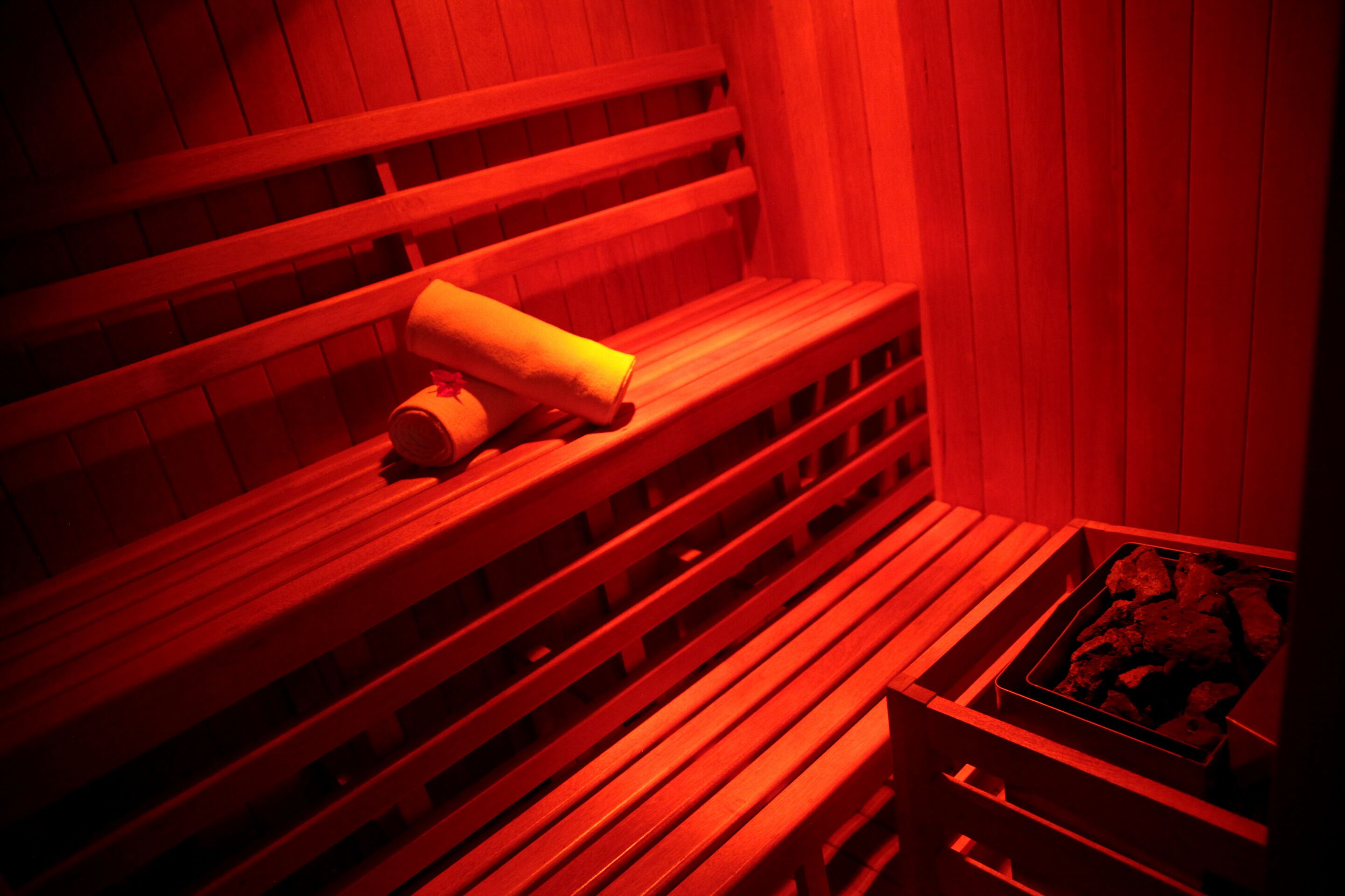 Una sauna con bancos de madera y un banco con una toalla.