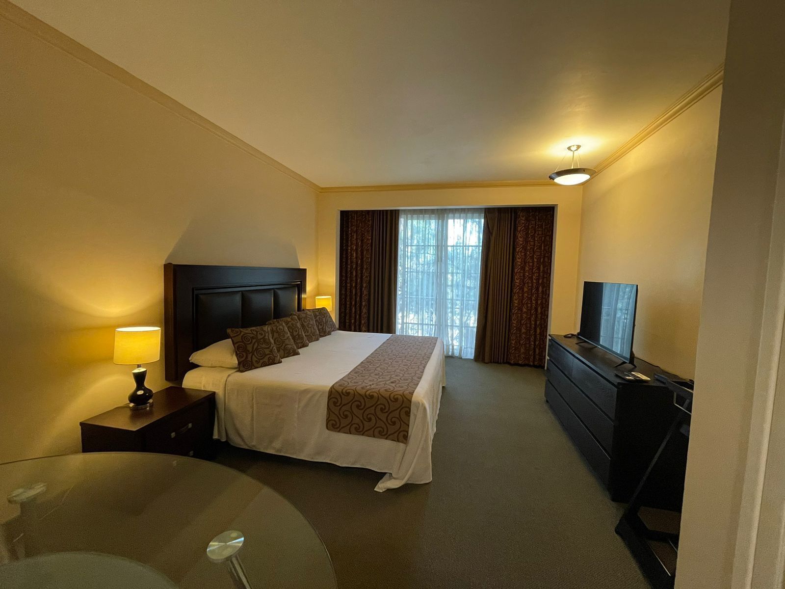 Quarto de hotel com cama, televisão, escrivaninha e cadeira.