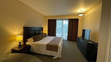 Quarto de hotel com cama, televisão, escrivaninha e cadeira.