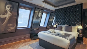 Un dormitorio moderno con una cama grande, un cabecero capitonado y obras de arte enmarcadas en las paredes.