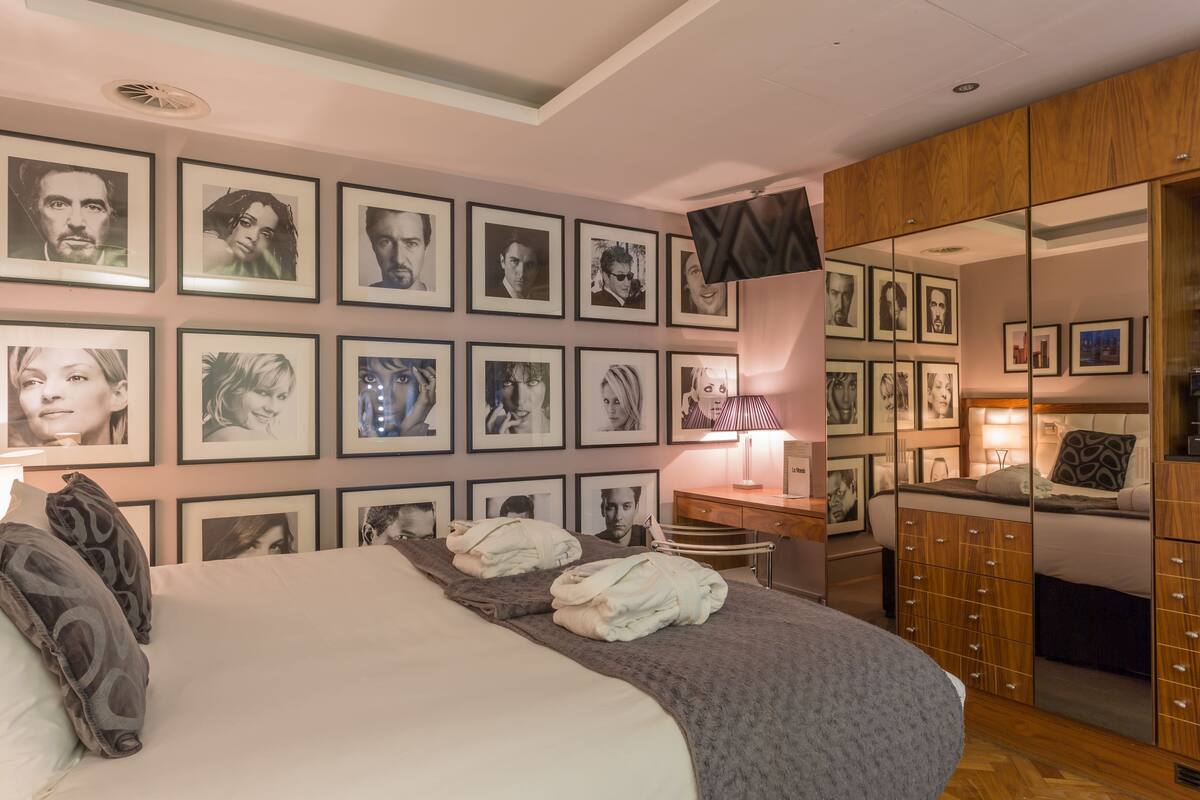 A bedroom with a large bed, a desk, and a wardrobe.