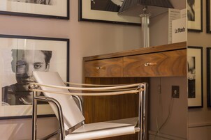 Ein modernes Zimmer mit einem stahlrohrgestellten Stuhl, einem Holzschrank und einem gerahmten Kunstwerk an der Wand.