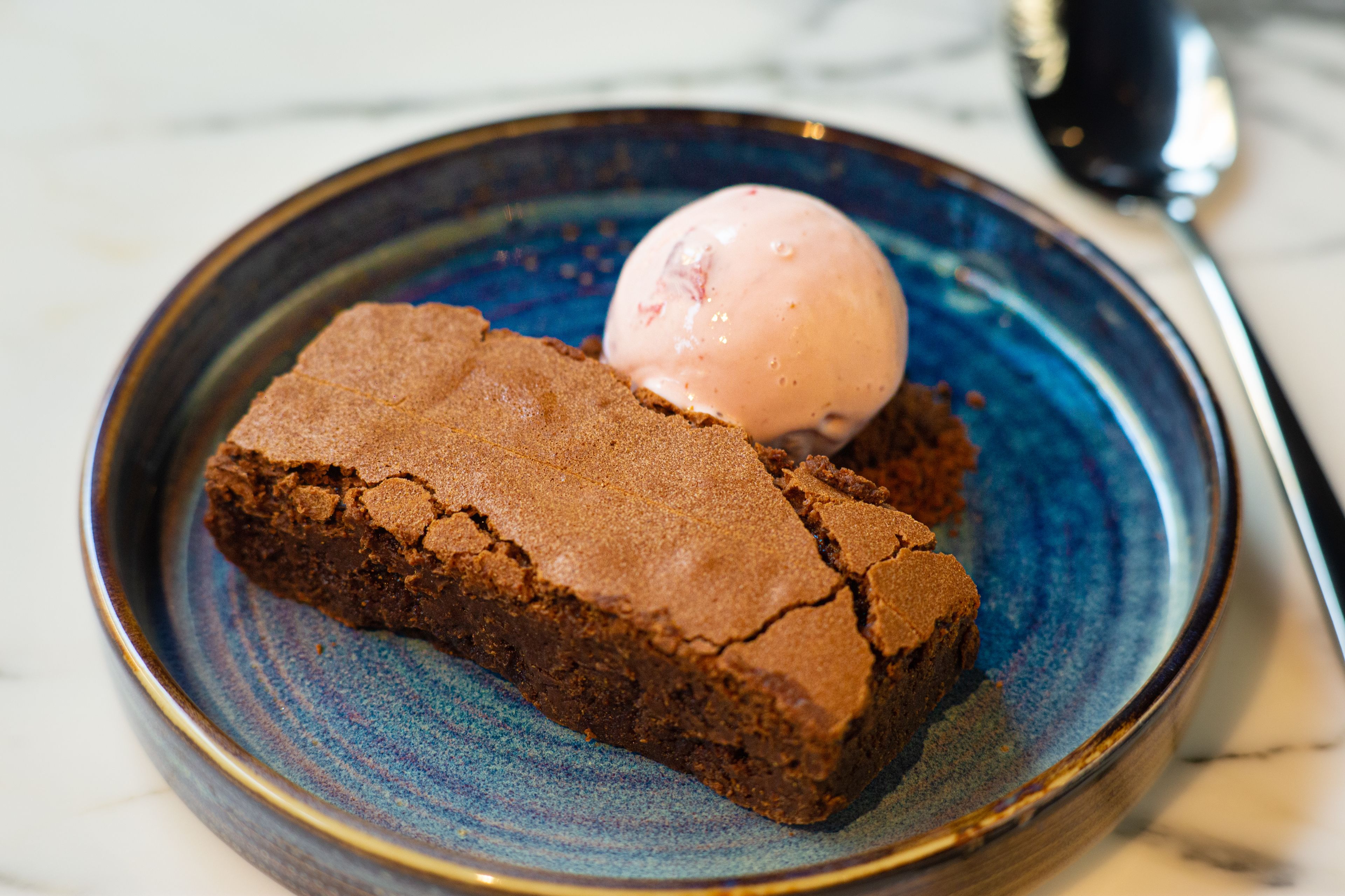 Un postre con una bola de helado en un plato.
