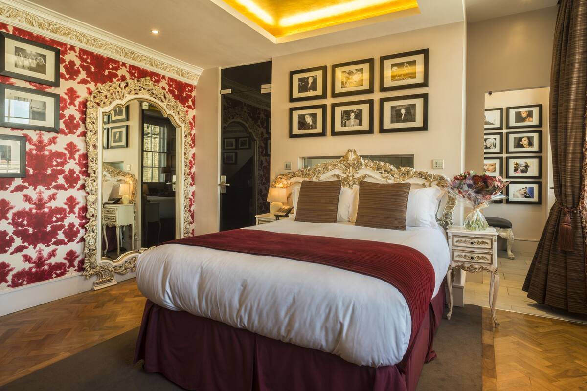 A spacious bedroom with a large bed, ornate headboard, and a mirror with a floral design.