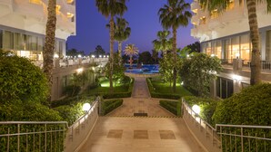 A hotel entrance with a pool, palm trees, and a well-lit pathway. - Terrace Beach Resort - All Inclusive (Manavgat)