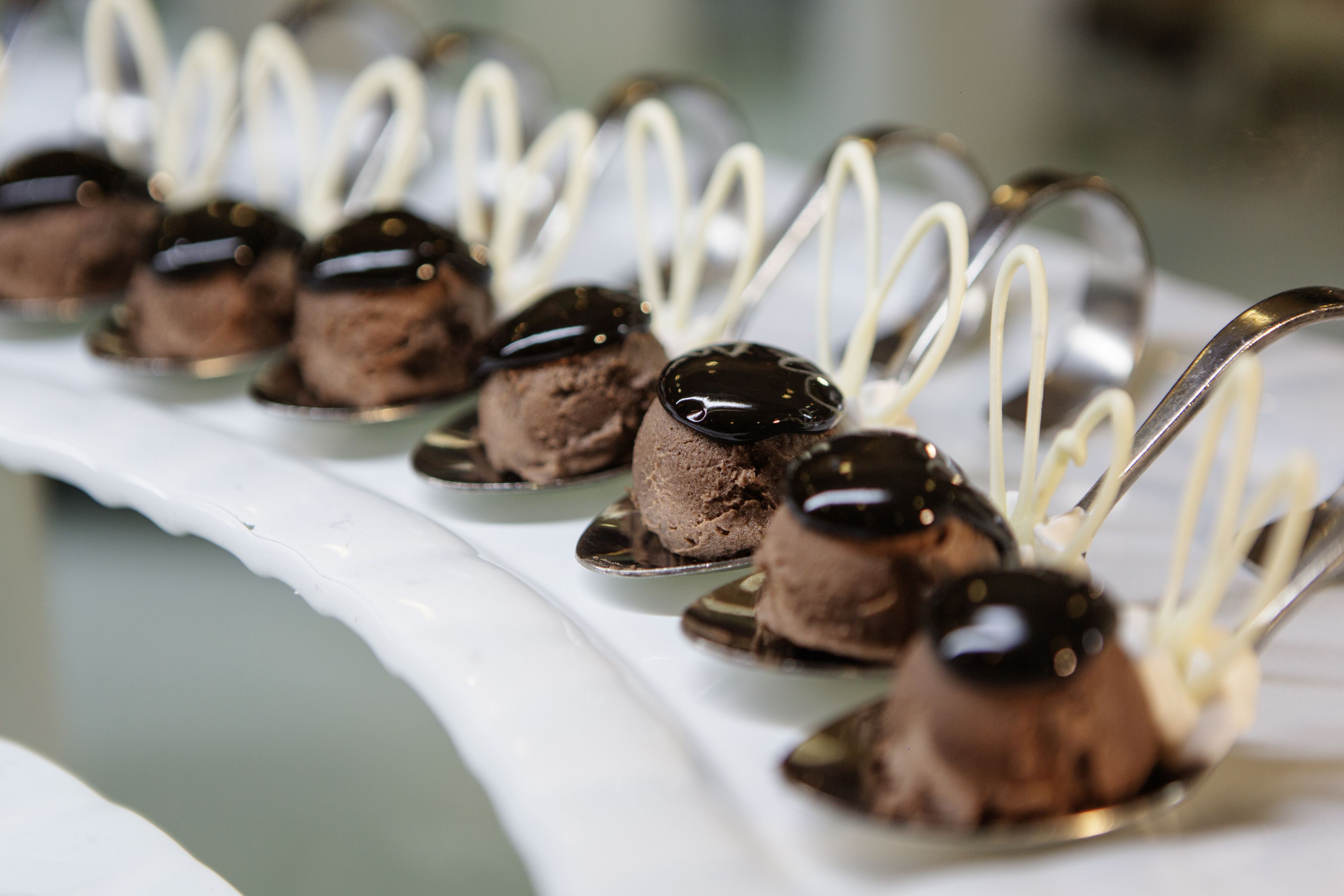 Een dessertschaal met chocolademousse, geserveerd op lepels.