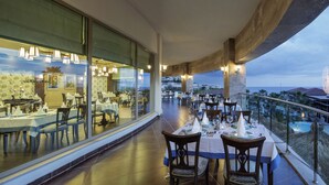 A restaurant with tables set for dining, large windows, and a view of a building and landscape. - Alba Royal Hotel - Ultra All Inclusive - Adults Only 16+ (Manavgat)