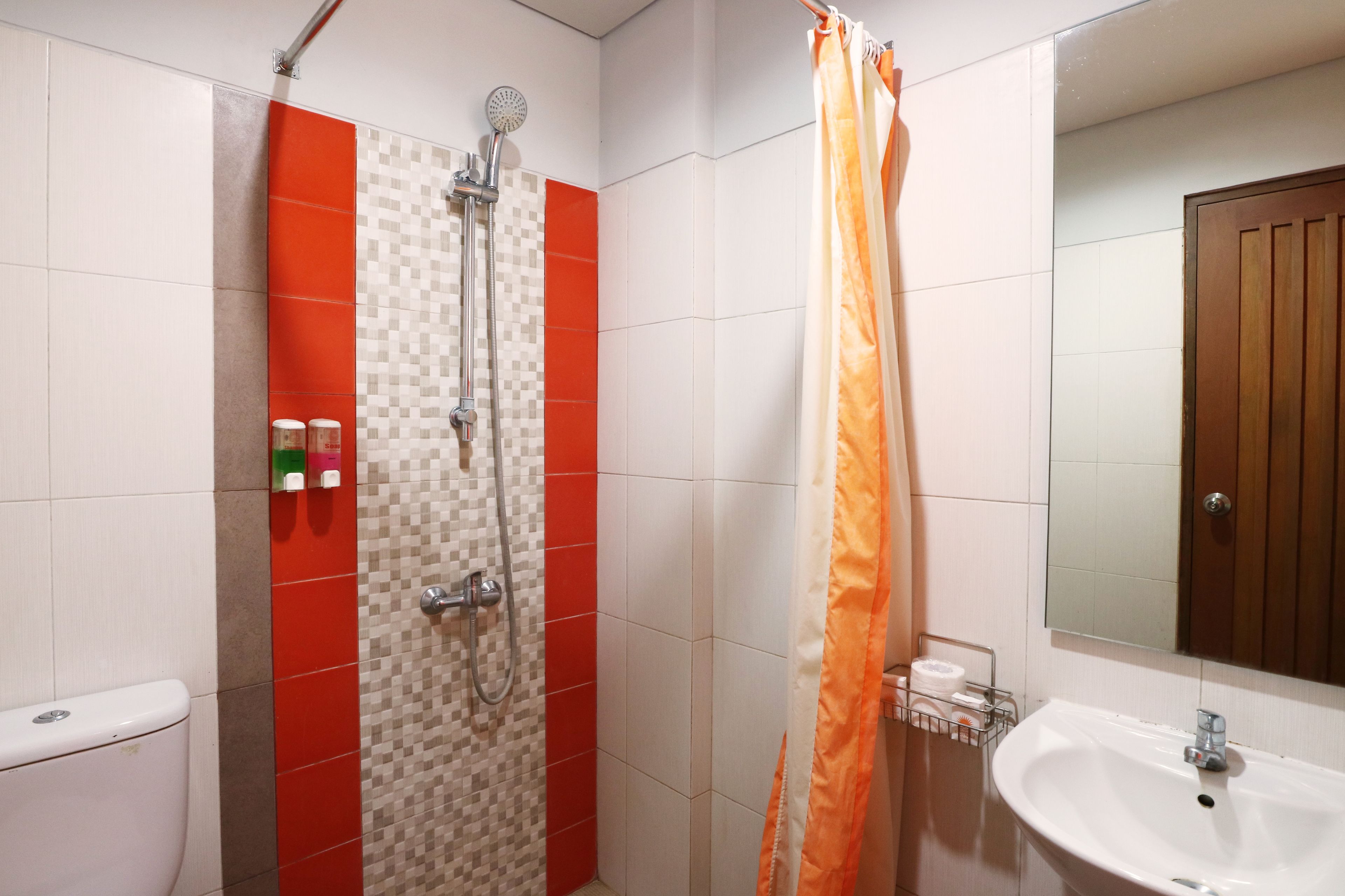 A bathroom with a shower, toilet, sink, and a mirror.