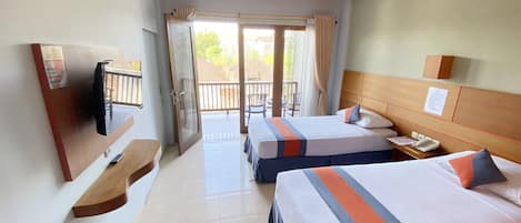 A hotel room with two beds, a TV, a desk with a phone, and a balcony with a view of the outside.