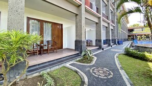 A hotel with a covered outdoor seating area, a pool, and a well-maintained garden. - Grand Sinar Indah Hotel (Legian)