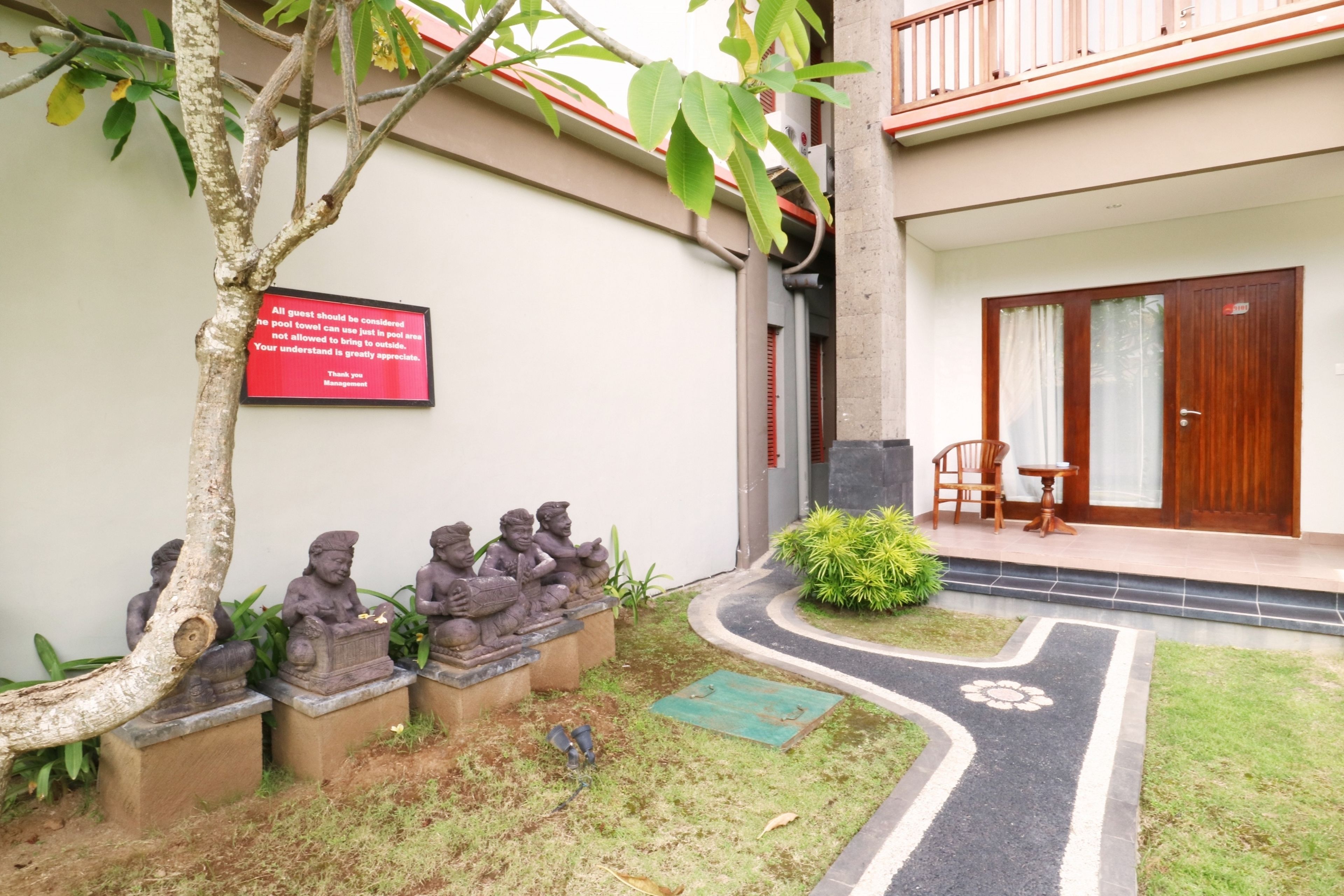 A courtyard with a statue of a child, a sign, and a small table with chairs.