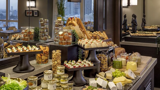 Un bufé con diversas opciones de comida, incluyendo quesos, frutas y pasteles.