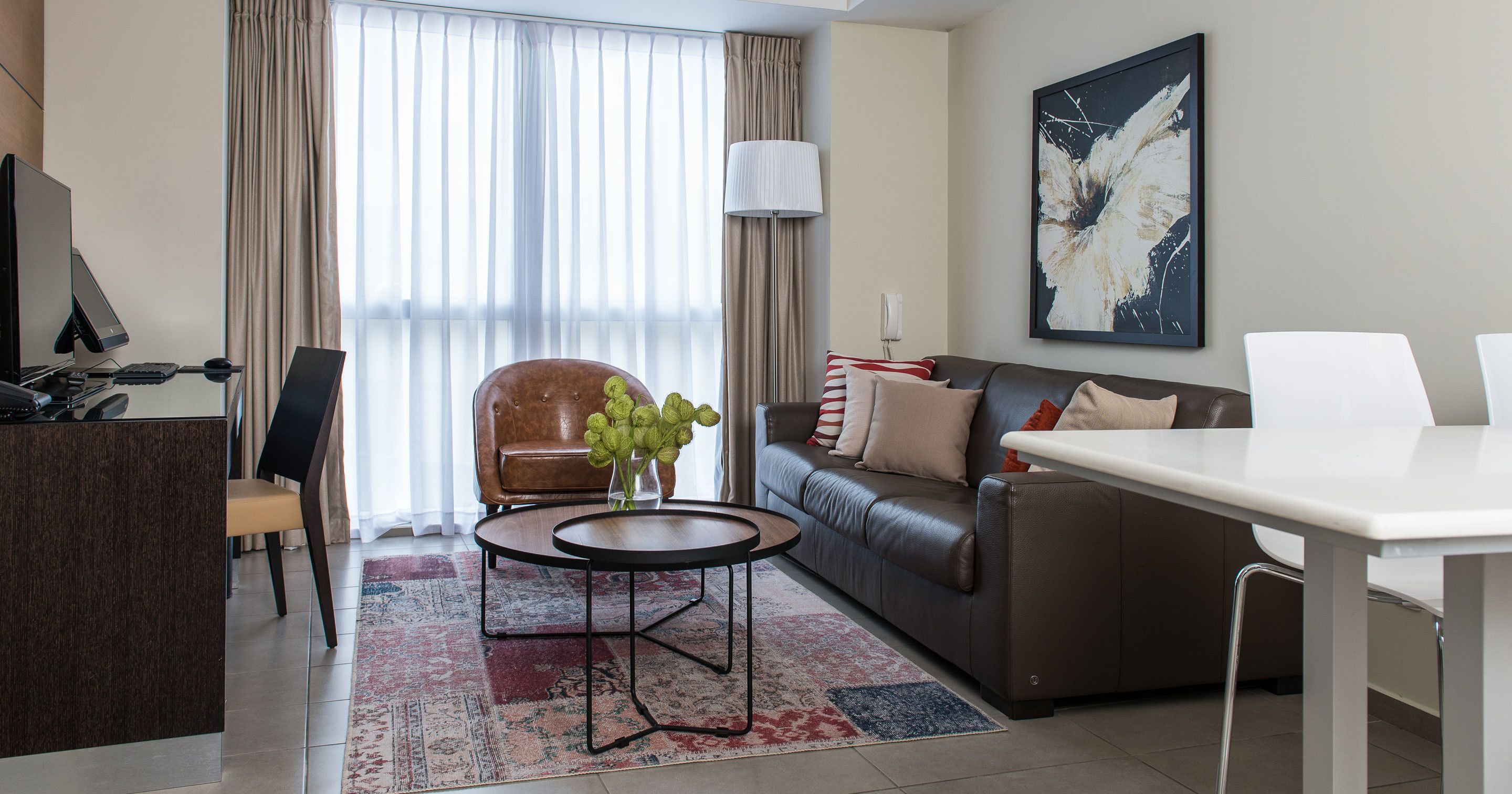 A modern living room with a sofa, a coffee table, a desk, and a computer setup.
