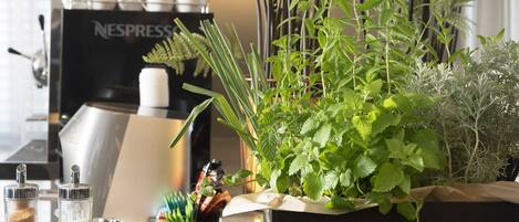 Una encimera de cocina con una cafetera, una planta de hierbas en maceta y varios utensilios de cocina.