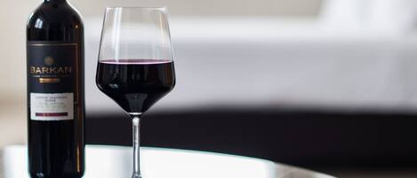 A bottle of wine and a glass of red wine on a table.
