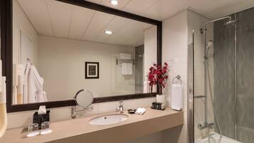 A modern bathroom with a large mirror, sink, and shower.