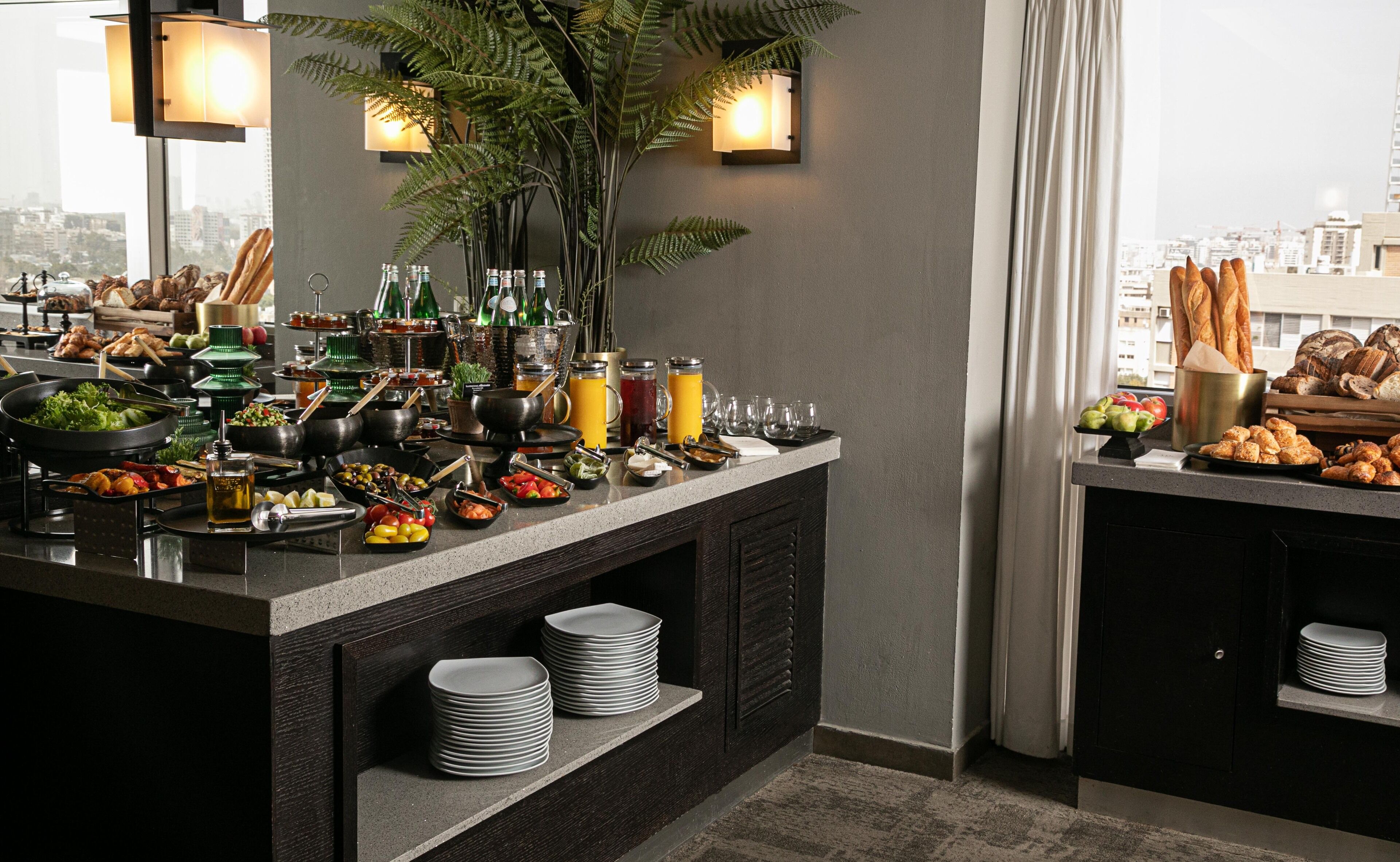 A buffet setup with various food items, drinks, and condiments.