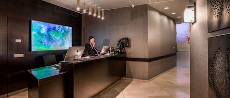 A reception desk with a large screen displaying abstract art, a modern interior design, and a clean, well-lit space.
