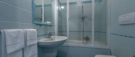 Un baño con lavamanos, inodoro y ducha con mampara de vidrio.