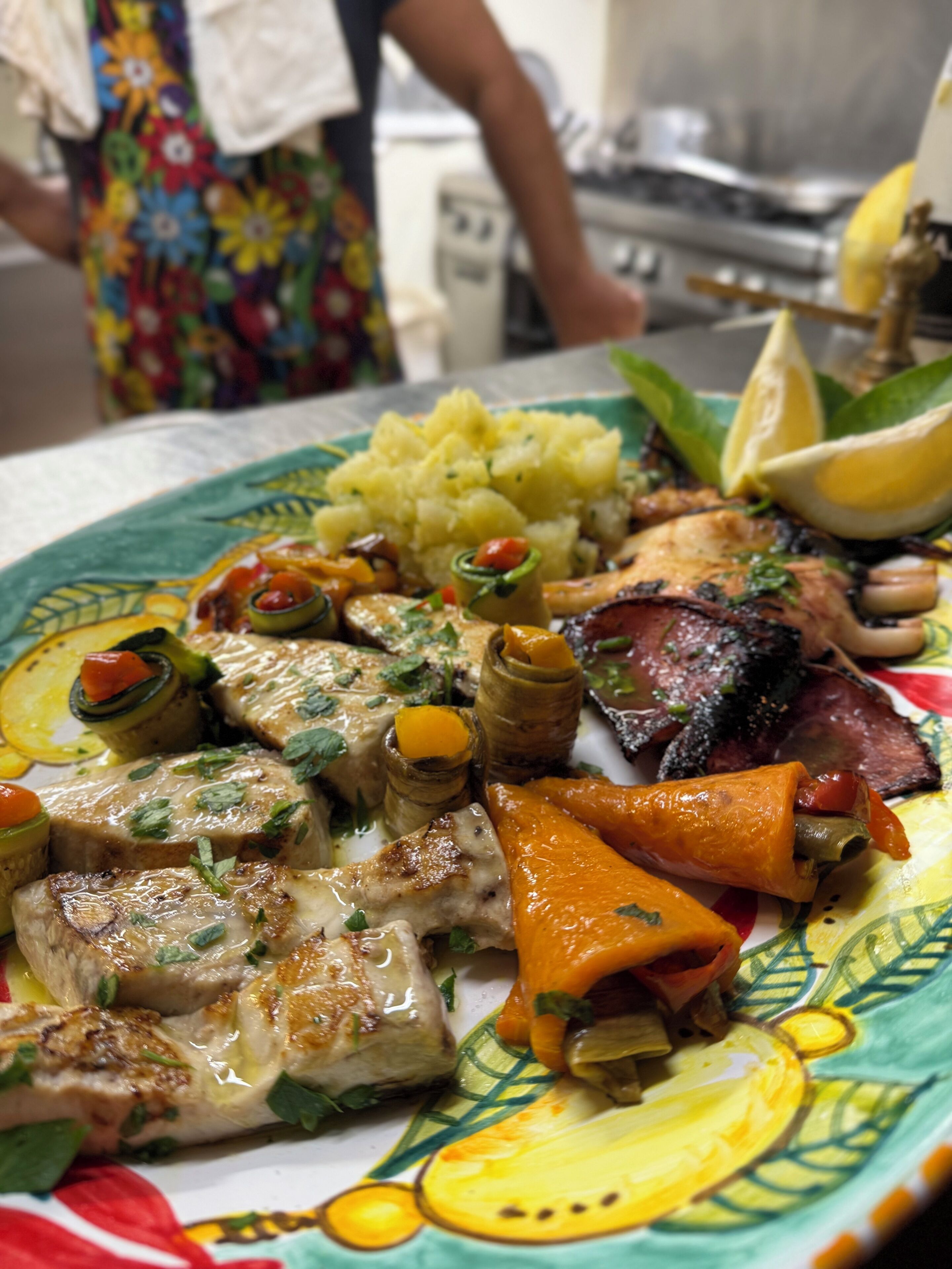 A plate of food with various meats, vegetables, and a lemon wedge.