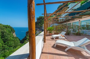 Una terraza con sillones blancos y vista al mar.
