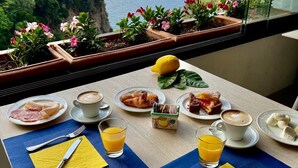 A table with breakfast items and a view of the sea. - Hotel La Pergola (Amalfi)