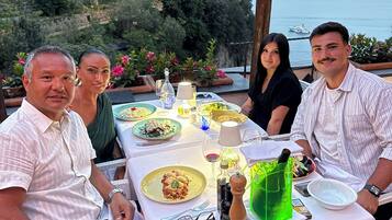 Una tavola imbandita per quattro persone, con piatti di cibo, bicchieri e una bottiglia d'acqua verde.