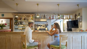 A bar area with a counter, bar stools, and a variety of bottles and glasses. - Hotel La Pergola (Amalfi)
