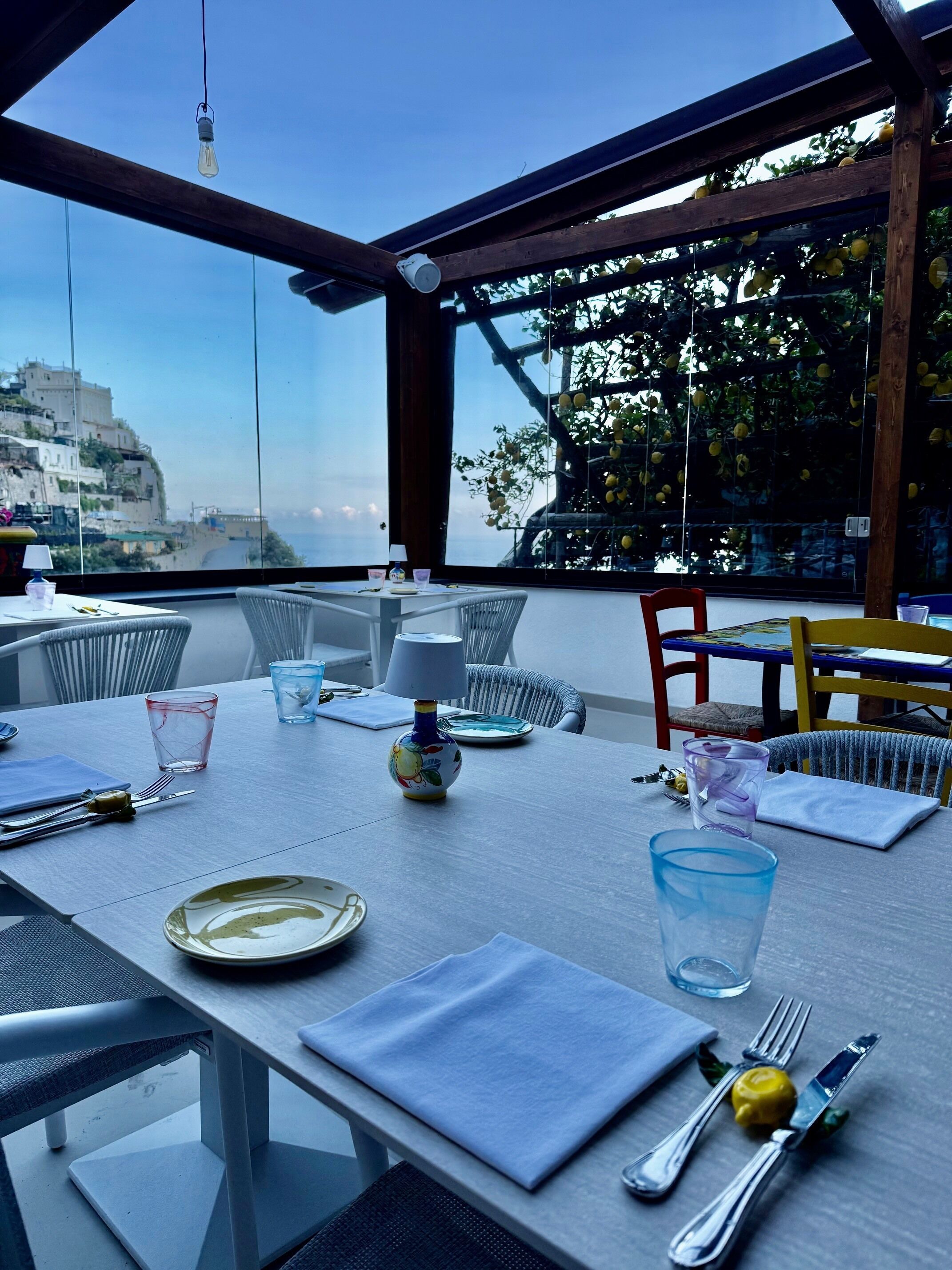 A table set for dining with a view of the sea and buildings in the background.