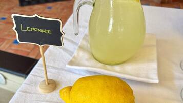 A pitcher of lemonade with a lemon and leaves on a table.