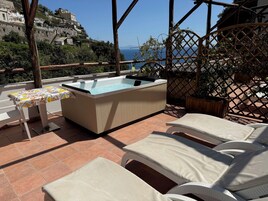 Terraza en la azotea con jacuzzi, sillas de descanso y una mesa con mantel estampado.